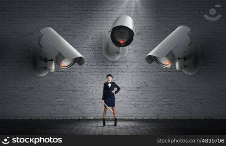 Camera keep an eye on woman. Young woman with bat under CCTV camera control