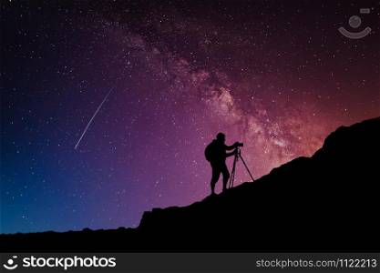 Camera man silhouette on the mountain over milky way night stars sky