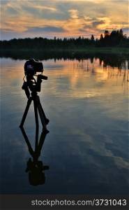 Camera on a tripod standing in the lake. Sunset on the lake. lake Moiseevskoe, Valdaysky district, Novgorod region, Russia&#xA;