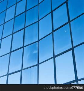 camera on part of modern office building facade in glass and steel with reflections of blue sky