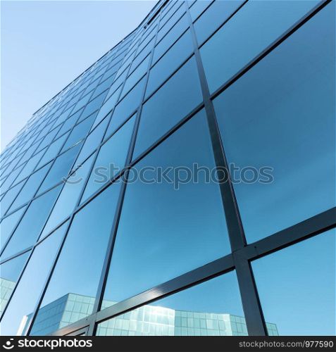 camera on part of modern office building facade in glass and steel with reflections of blue sky