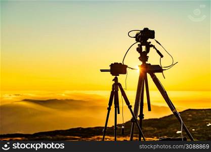 Camera on tripod take photo from burning sunset above clouds.. Camera on tripod take photo from sunset above clouds