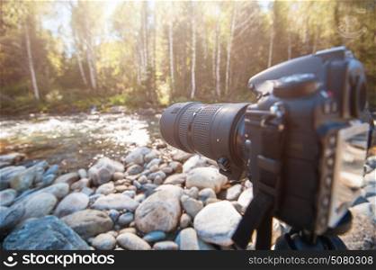 Camera with telephoto lens. Camera with telephoto lens on a tripod takes photo at nature