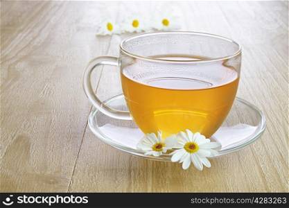 Camomile tea in glass cup on vintage wooden table