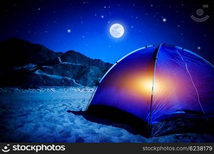 Camp on sandy beach, tent at the night with light inside, moon light, active tourism, hiking and traveling concept