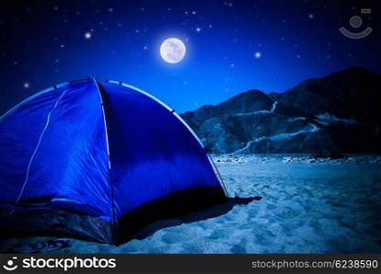 Camp tent on the beach at night, full moon glowing in dark night, summer adventure and active lifestyle concept&#xA;