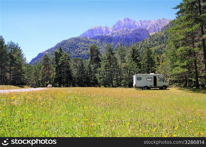 Camper autocaravan meadow in Pyrenees mountain sunny day pine trees forest