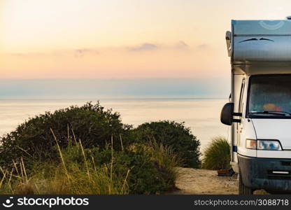 Camper rv at sunrise dawn on mediterranean coast in Spain. Camping on sea shore. Vacation trip in motor home.. Camper vehicle on seashore at sunrise dawn