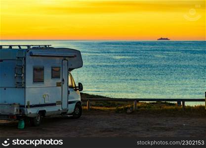 Camper rv at sunrise on mediterranean coast in Spain. Camping on nature beach. Vacation and trip in motor home.. Camper vehicle on beach at sunrise
