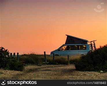 Camper van with roof top tent camping on mediterranean coast. Holidays and travel in motorhome.. Camper van with roof top tent camp on beach