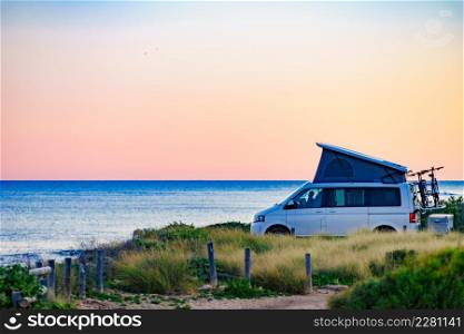 Camper van with roof top tent camping on mediterranean sea coast. Holidays and travel in motorhome.. Camper van with roof top tent camp on beach