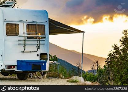 Camper vehicle with roll out awning and tourist table with chairs in french mountains. Camping on nature. Holidays and travel with motor home.. Camper camping in mountain