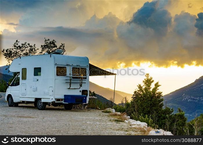 Camper vehicle with roll out awning and tourist table with chairs in french mountains. Camping on nature. Holidays and travel with motor home.. Camper camping in mountain
