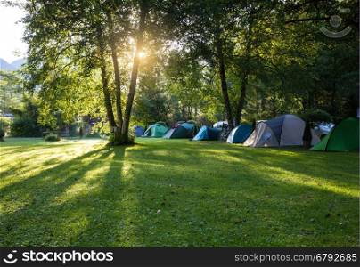Camping area with tents on green grass lawn