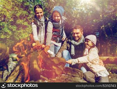 camping, hike and people concept - happy family roasting marshmallow over campfire. happy family roasting marshmallow over campfire