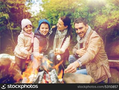 camping, hike and people concept - happy family roasting marshmallow over campfire. happy family roasting marshmallow over campfire