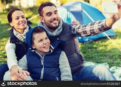 camping, hike, technology and people concept - happy family with smartphone taking selfie at campsite. family with smartphone taking selfie at campsite