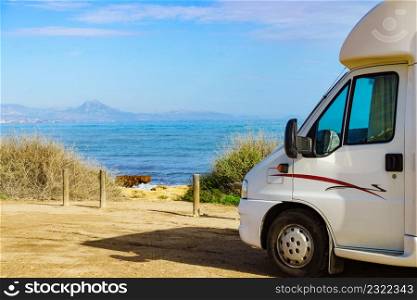 Camping on sea shore. Camper vehicle on beach, mediterranean coast in Spain. Traveling, active lifestyle.. Camper on beach seashore. Holidays trip.