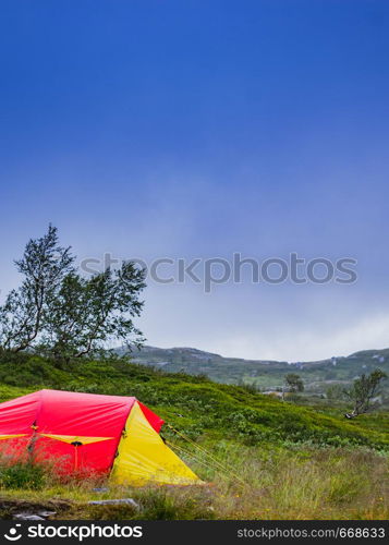 Camping. Red yellow tent on nature in summer. Holidays and travel.. Red tent on nature. Camping