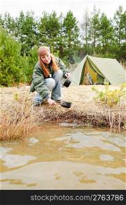 Camping tent happy woman washing dishes in water stream