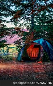 Camping Tent Standing in the Beautiful Cedars Forest in the Mountains. People Sleeping in the Forest. Enjoying Nature and Active Life.