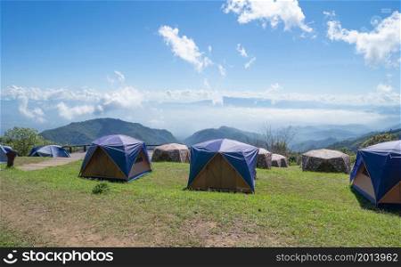 Camping tents area on mountain hill with trees on blue sky in travel trip, nature environment landscape, Chiang Mai, Northern of Thailand. National park.