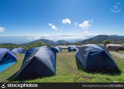 Camping tents area on mountain hill with trees on blue sky in travel trip, nature environment landscape, Chiang Mai, Northern of Thailand. National park.