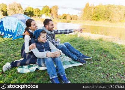 camping, tourism, hike and people concept - happy family over tent at camp site pointing finger to something