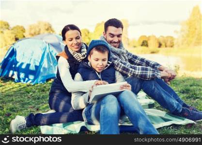camping, tourism, hike, technology and people concept - happy family with tablet pc computer and tent at camp site. happy family with tablet pc and tent at camp site