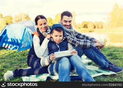 camping, tourism, hike, technology and people concept - happy family with tablet pc computer and tent at camp site. happy family with tablet pc and tent at camp site. happy family with tablet pc and tent at camp site