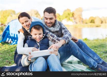 camping, tourism, hike, technology and people concept - happy family with tablet pc computer and tent at camp site