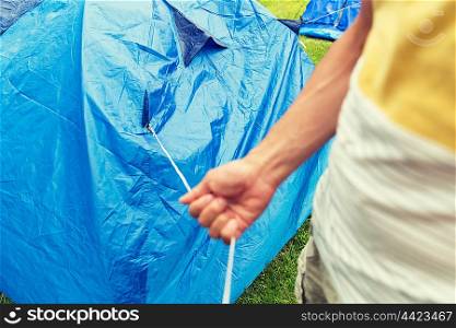 camping, travel, tourism, hike and people concept - close up of man setting up tent outdoors