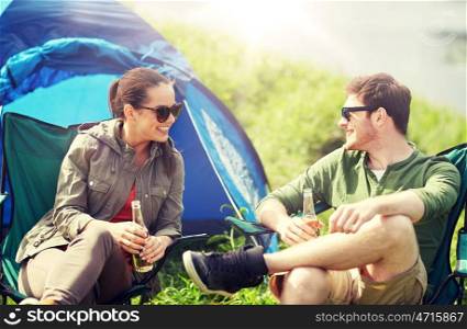 camping, travel, tourism, hike and people concept - happy couple drinking beer or cider at campsite tent. happy couple drinking beer at campsite tent. happy couple drinking beer at campsite tent