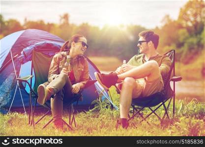 camping, travel, tourism, hike and people concept - happy couple drinking beer or cider at campsite tent. happy couple drinking beer at campsite tent
