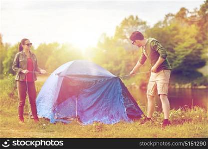 camping, travel, tourism, hike and people concept - happy couple setting up tent outdoors. happy couple setting up tent outdoors