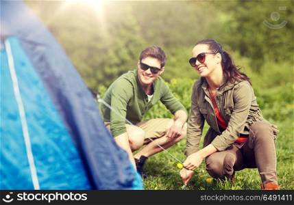 camping, travel, tourism, hike and people concept - happy couple setting up tent outdoors. happy couple setting up tent outdoors. happy couple setting up tent outdoors