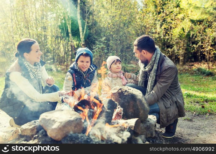 camping, travel, tourism, hike and people concept - happy family roasting marshmallow over campfire. happy family roasting marshmallow over campfire