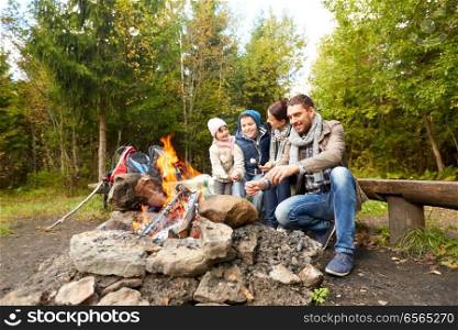 camping, travel, tourism, hike and people concept - happy family roasting marshmallow over campfire. happy family roasting marshmallow over campfire