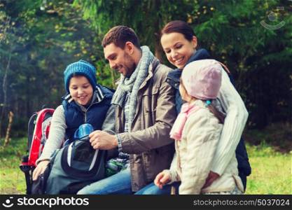 camping, travel, tourism, hike and people concept - happy family with backpacks and thermos at camp. happy family with backpacks and thermos at camp