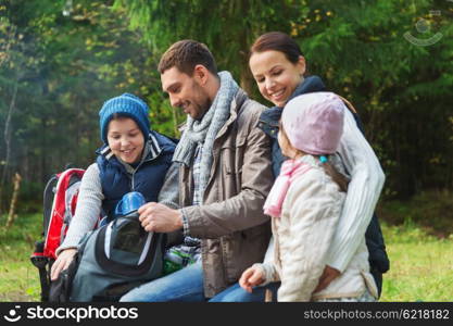 camping, travel, tourism, hike and people concept - happy family with backpacks and thermos at camp