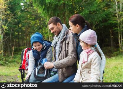 camping, travel, tourism, hike and people concept - happy family with backpacks and thermos at camp