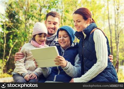 camping, travel, tourism, hike and people concept - happy family with tablet pc computer at camp in woods. happy family with tablet pc at camp