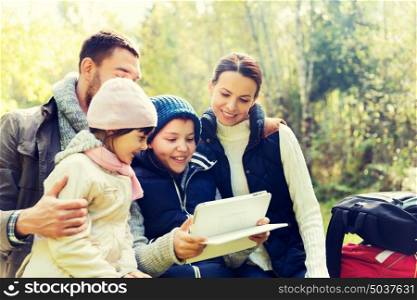 camping, travel, tourism, hike and people concept - happy family with tablet pc computer and backpacks at camp in woods. happy family with tablet pc and backpacks at camp