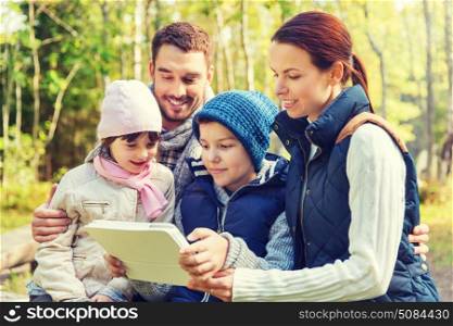camping, travel, tourism, hike and people concept - happy family with tablet pc computer at camp in woods. happy family with tablet pc at camp. happy family with tablet pc at camp