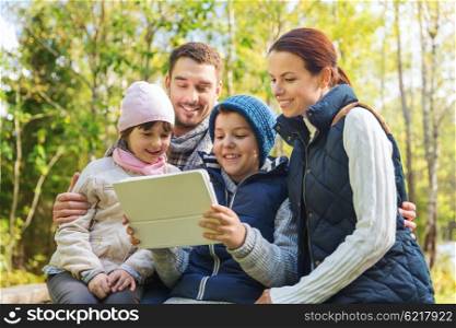 camping, travel, tourism, hike and people concept - happy family with tablet pc computer at camp in woods