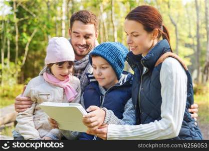 camping, travel, tourism, hike and people concept - happy family with tablet pc computer at camp in woods