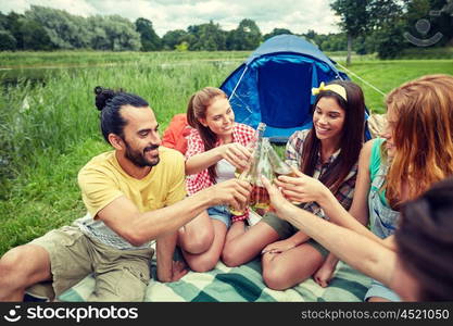 camping, travel, tourism, hike and people concept - happy friends with glass bottles drinking cider or beer at campsite