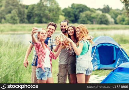 camping, travel, tourism, hike and people concept - happy friends with glass bottles drinking cider or beer and taking selfie by smartphone at camping