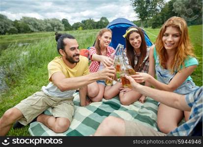 camping, travel, tourism, hike and people concept - happy friends with glass bottles drinking cider or beer at campsite