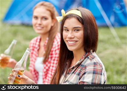 camping, travel, tourism, hike and people concept - happy young women with glass bottles drinking cider or beer at campsite